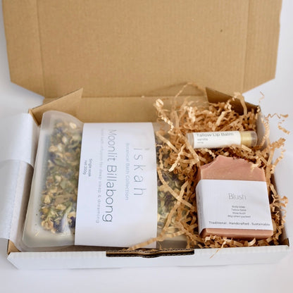 Open cardboard box with natural products including a soap bar and a jar on a white background